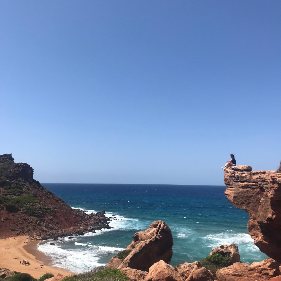 Donna su uno sperone a Cala del Pilar - Minorca, Isole Baleari, Spagna