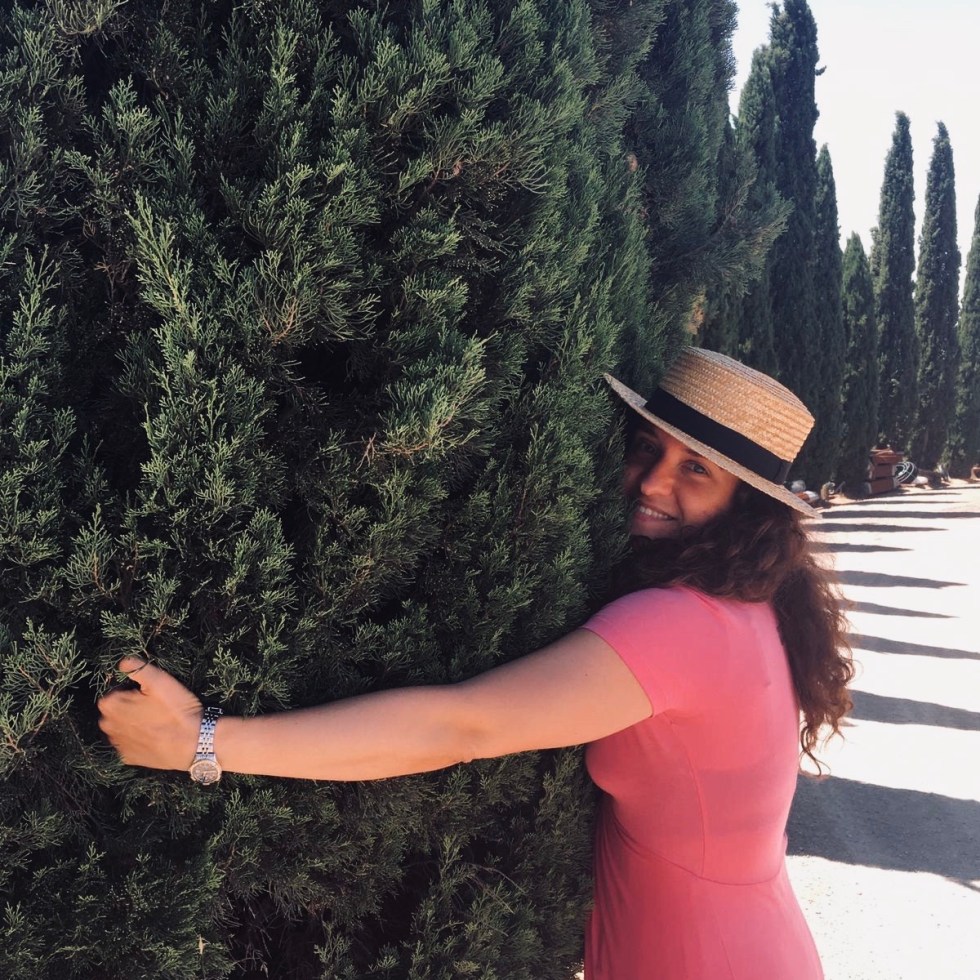 Donna abbraccia un cipresso in Val d'Orcia - Toscana, Italia