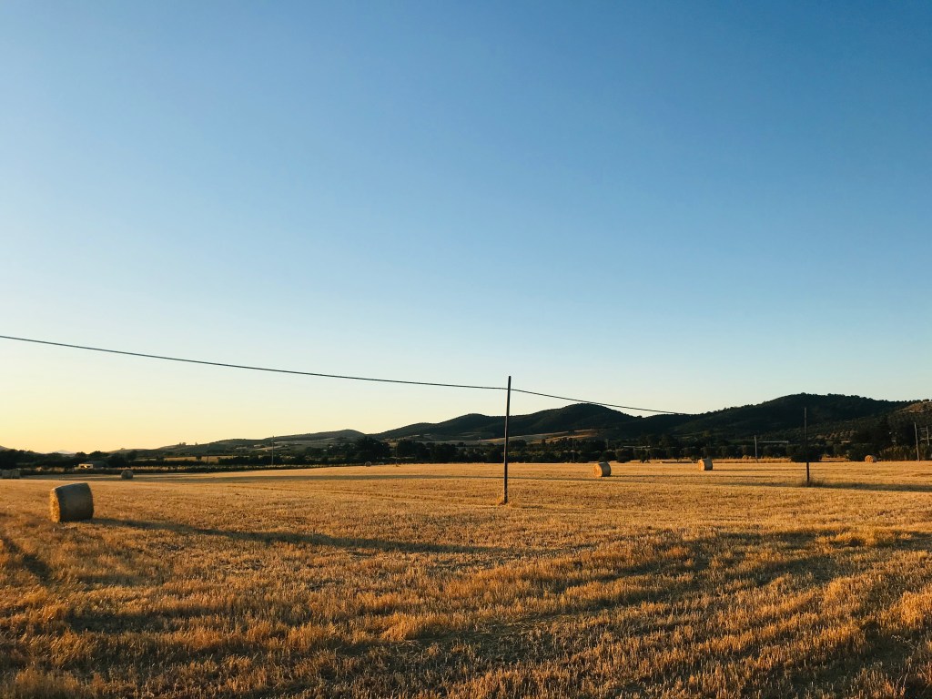 Campi con balle di fieno al tramonto - Maremma, Toscana, Italia