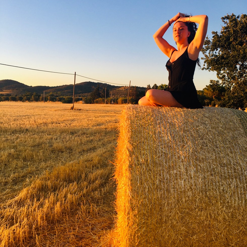 Donna posa su una balla di fieno al tramonto - Maremma toscana, Italia