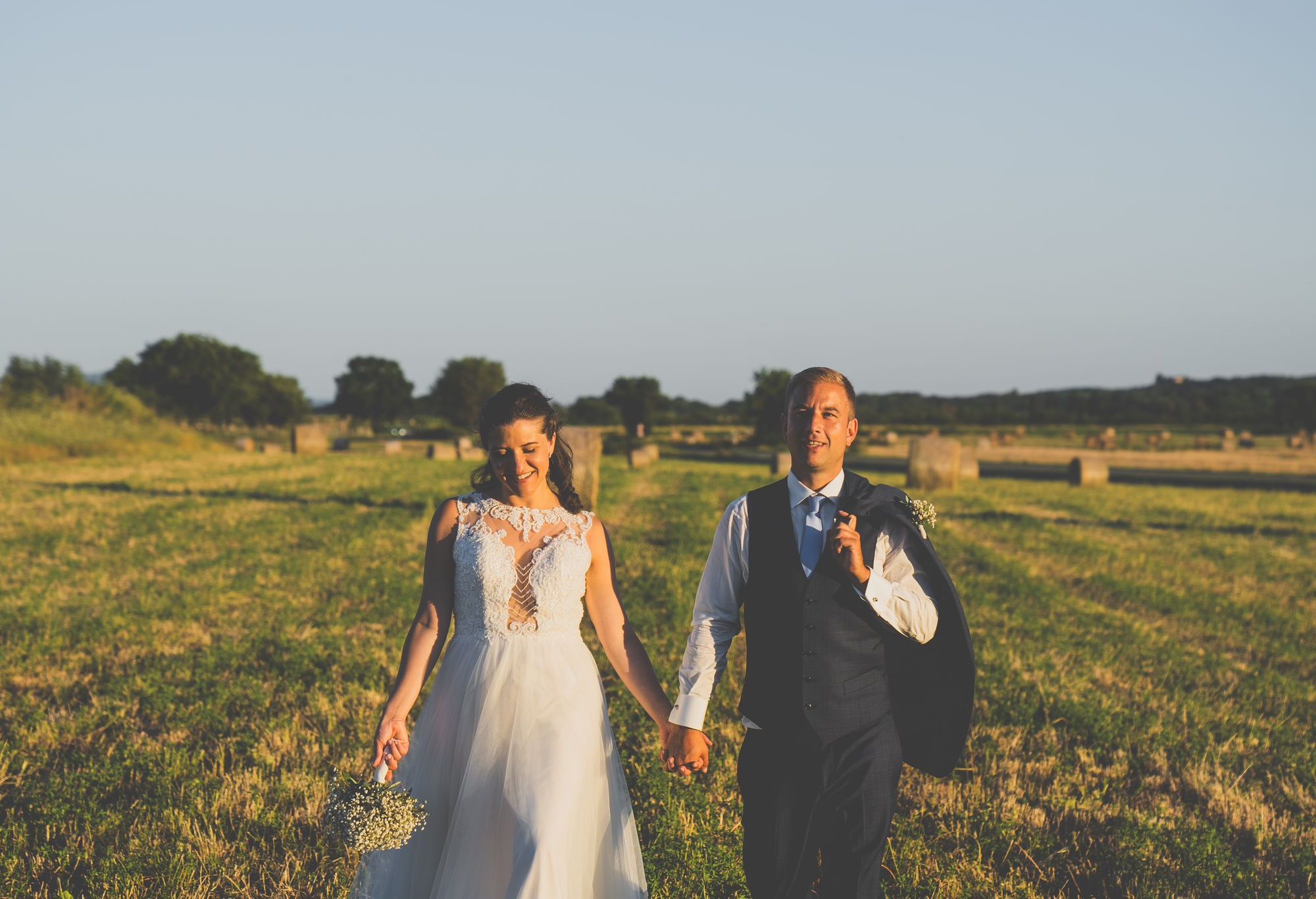 Coppia di sposi mano nella mano in un campo - Vetulonia, Maremma Toscana, Italia