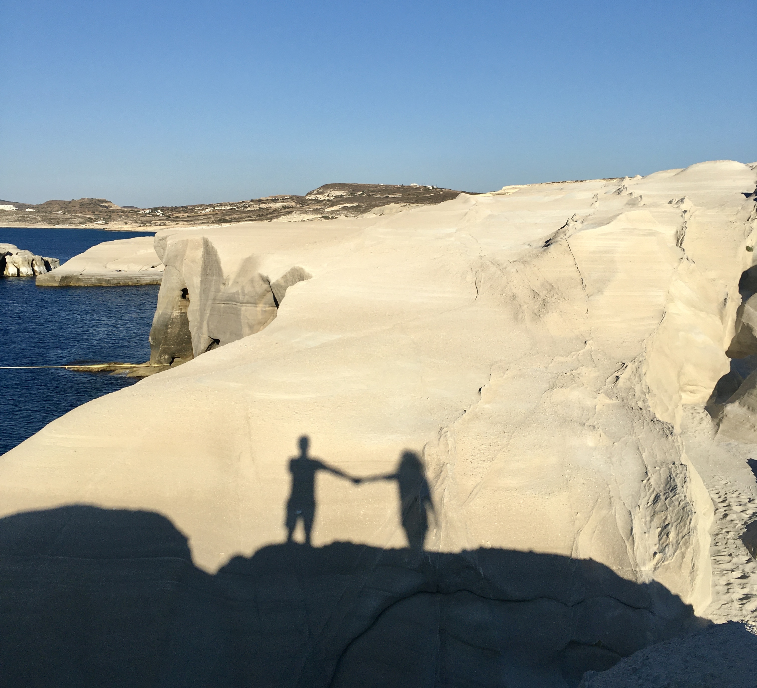 Ombre di donna e uomo che si danno la mano a Sarakiniko - Milos, Isole Cicladi, Grecia
