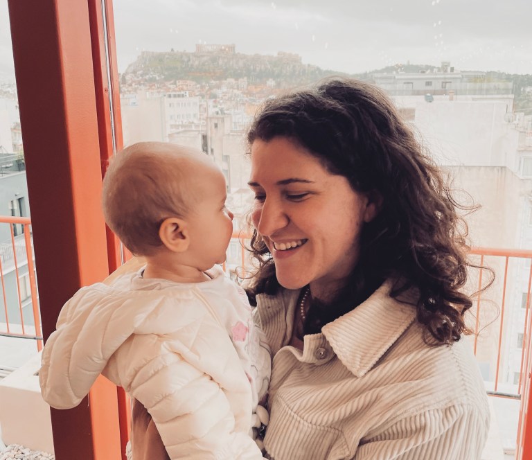 Donna sorride alla sua bambina piccola su una terrazza vista Acropoli - Atene, Grecia